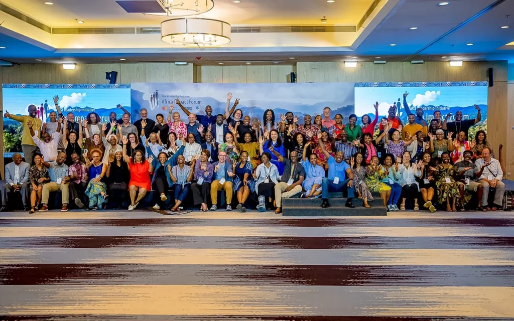 Pan-African gathering of ALI fellows and partners posing together on stage at the Africa Impact Forum.