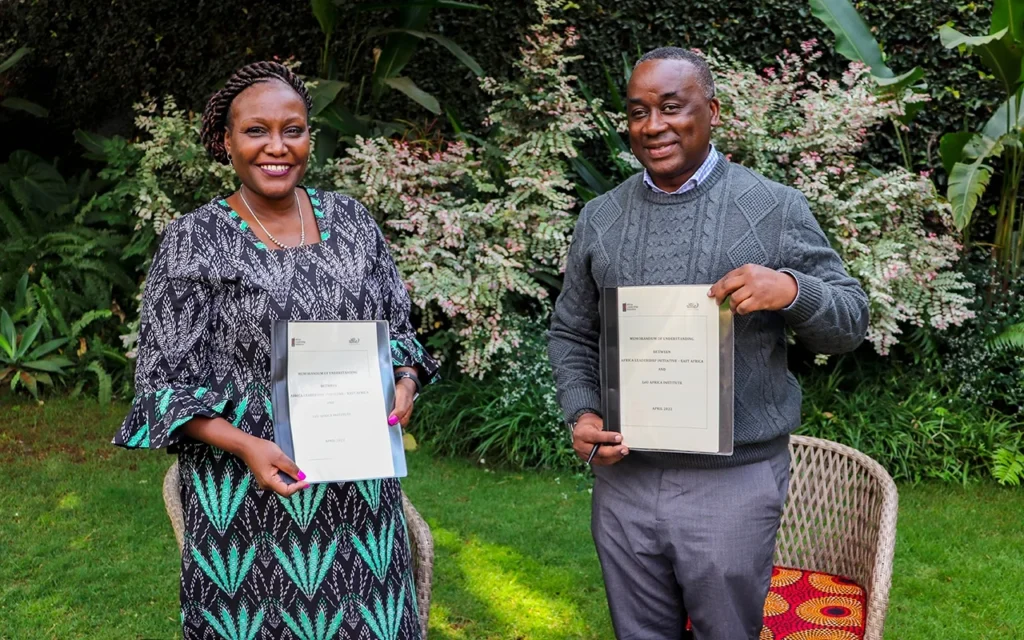 Representatives from ALI-East Africa and Leo Africa Institute holding a signed memorandum of understanding in a garden setting.