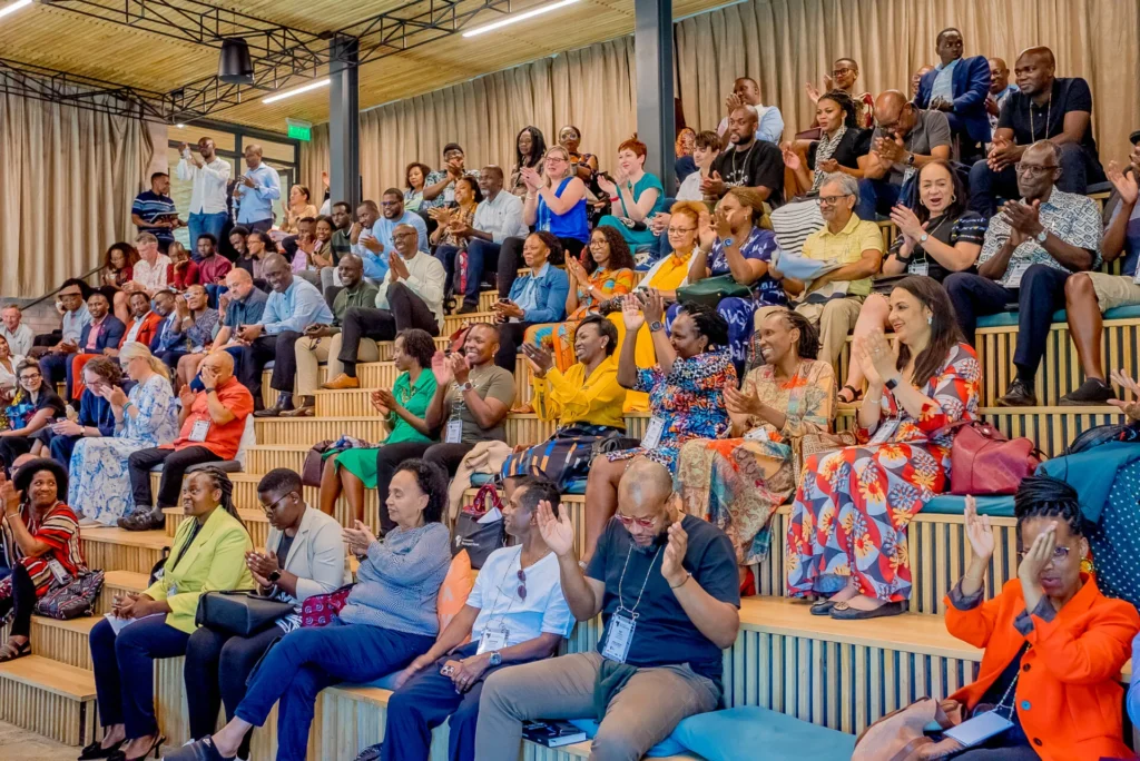 Tiered auditorium of ALI-East Africa fellows applauding during an interactive leadership session.