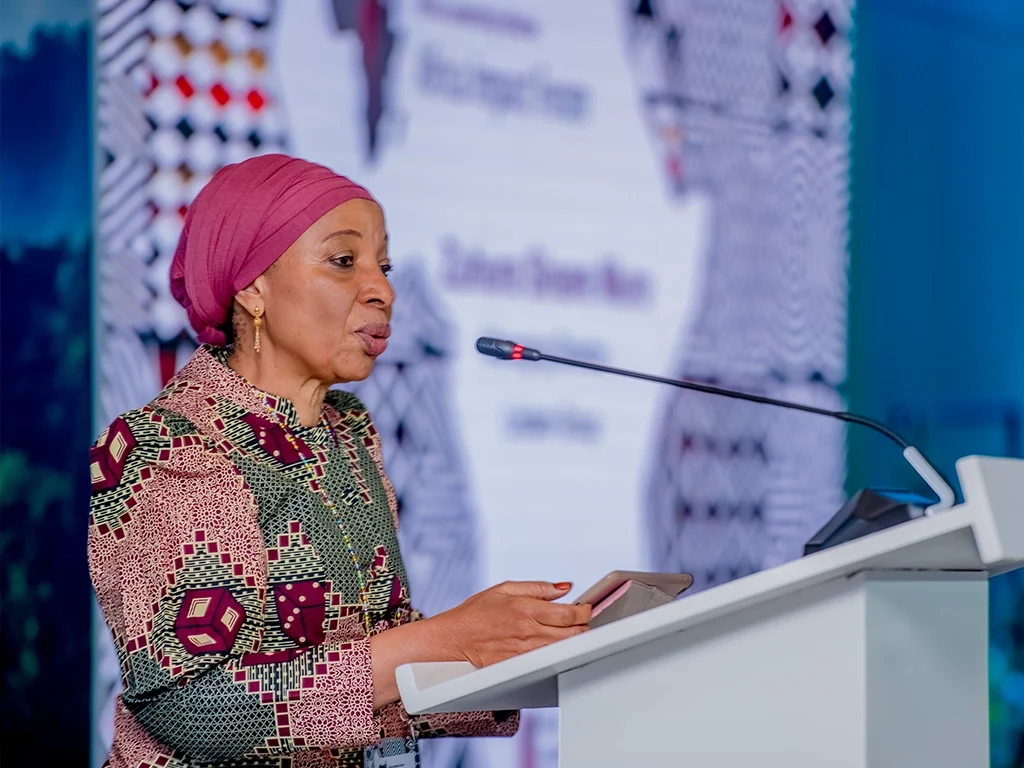 Female speaker in a patterned dress and pink head-wrap delivering a keynote on values-driven leadership at an ALI-East Africa forum.
